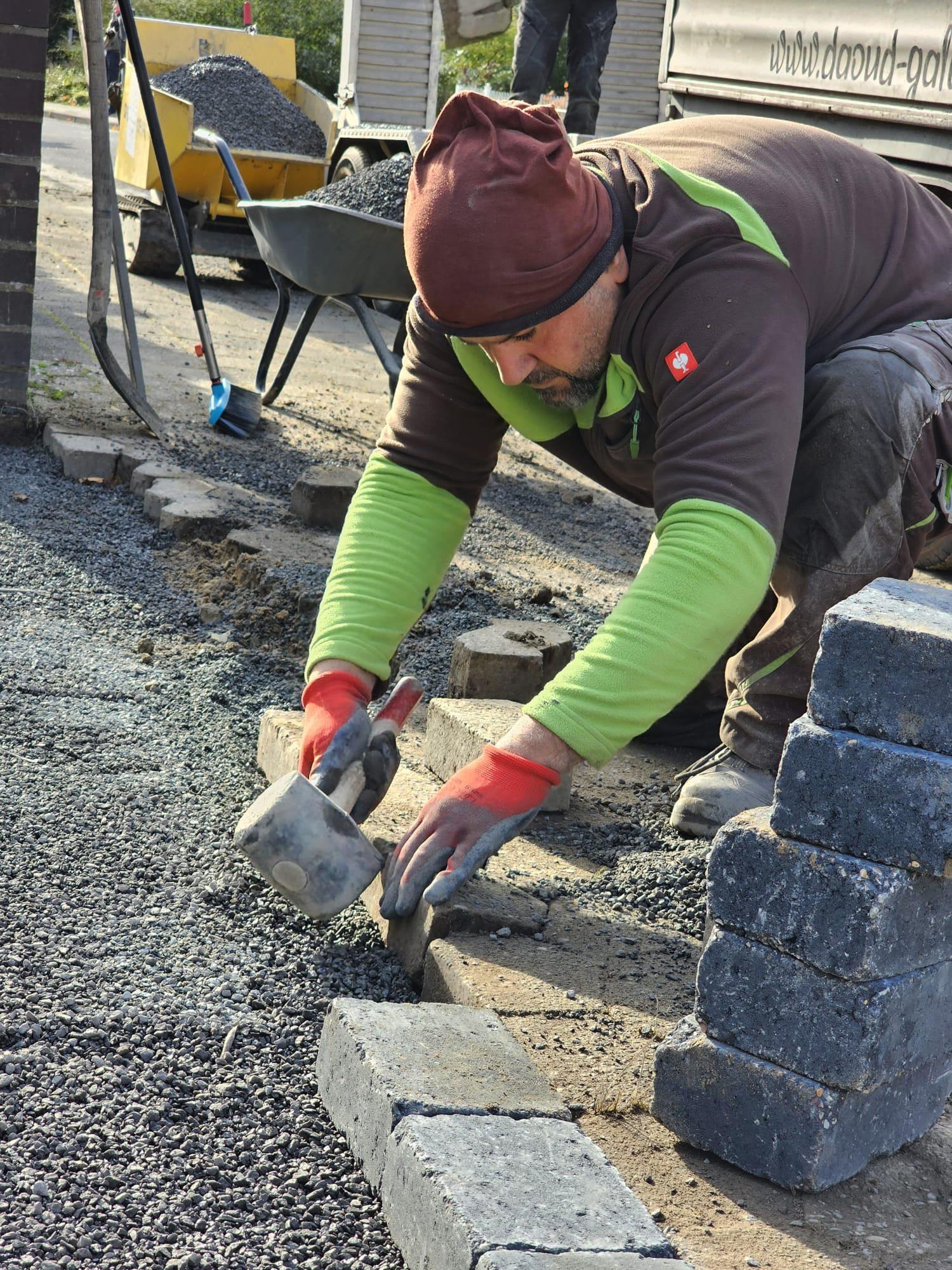 Bazid Daoud setzt Randsteine auf einer Pflasterbaustelle